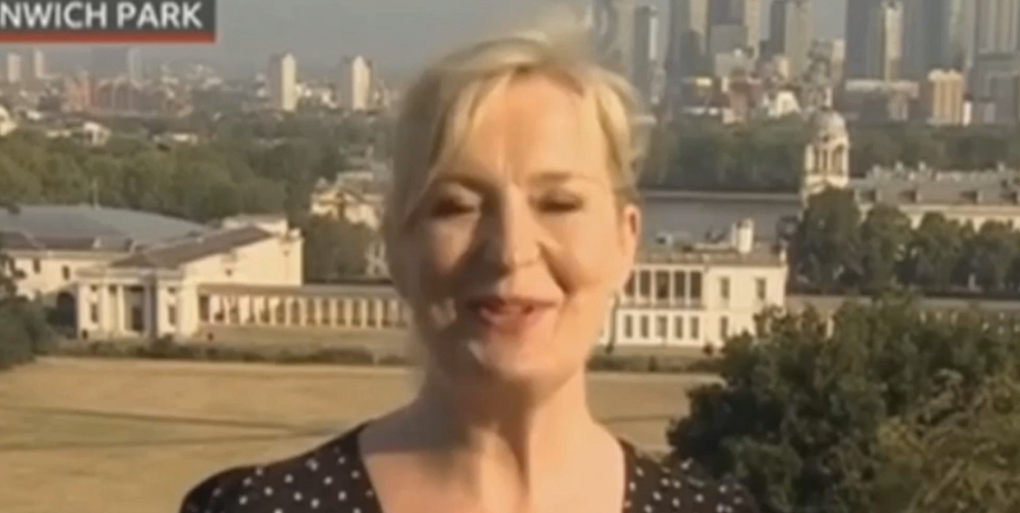 BBC reporter in front of the camera with a surprised expression, capturing the moment of the accidental slip-up in Greenwich Park. Lush greenery and towering trees in the background. A snapshot of unexpected hilarity!