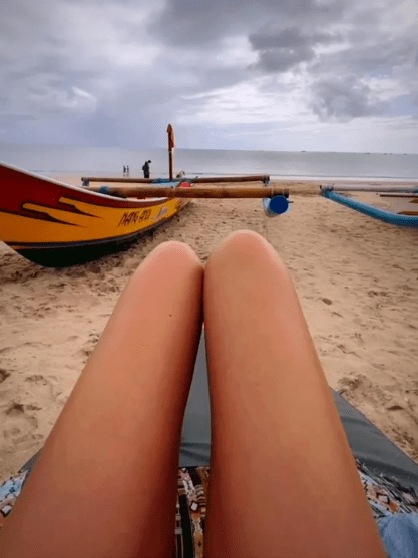 An image showing a pair of legs lying on a beach with hot dogs positioned to look like they are the legs.