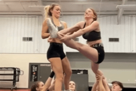 Two cheerleaders are thrown high into the air by their teammates during a training session, showcasing their athleticism and coordination.