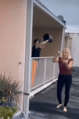 Woman throws a bucket of water, accidentally hitting her friend instead of the person recording.