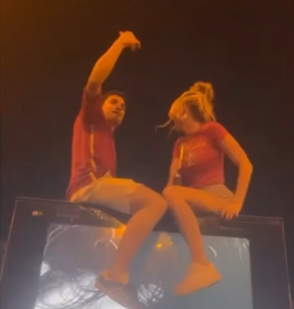 Man dodging a kiss from a woman during a Euro celebration on top of an advertisement sign.