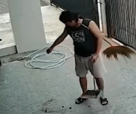 Man sweeping with a misplaced brush tucked between his arm and body.