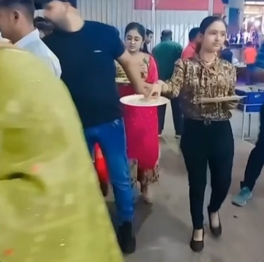 A woman at the buffet grabs the last piece of food from a man’s plate while he is distracted.