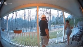 A couple standing at the entrance of a house, looking surprised as their kid shouts from inside.