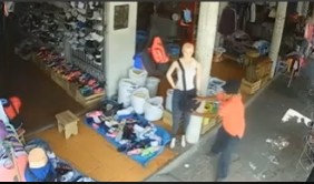 The thief grips the mannequin’s handbag strap and leans back, exerting force.