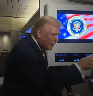 Donald Trump pointing toward a Bloomberg reporter while interrupting her during a press gaggle.