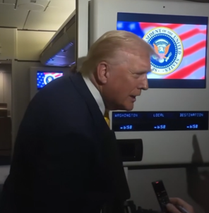 Donald Trump listening with a serious expression during a conversation with reporters aboard Air Force One.