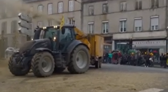 Tractor parked across the entrance of an official building with protesters and supporters gathered behind it.