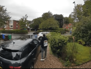 wo neighbours stand beside a blocked driveway arguing next to a parked car.