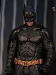 A person dressed as Batman wearing a black cowl and cape, standing confidently against an urban backdrop, symbolizing pop culture fandom and record-breaking costume events.