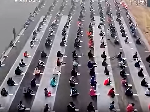 Aerial view of thousands of candidates sitting in rows on an asphalt airport runway for an exam in Odisha.