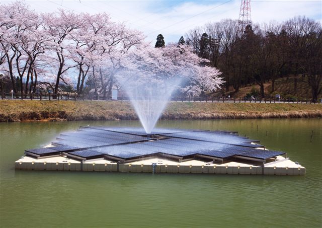 Floating solar panels spread across calm water near a port, illustrating Spain’s open-sea solar pilot.