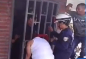 Woman with her head stuck between metal gate bars after attempting to look outside.