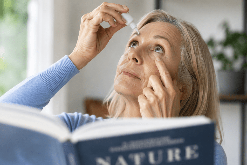 Person using eye drops to improve near vision while reading a book