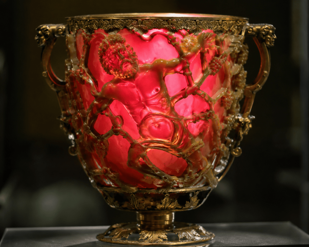 Ancient Roman Lycurgus Cup glowing red when backlit, showing carved mythological figures.