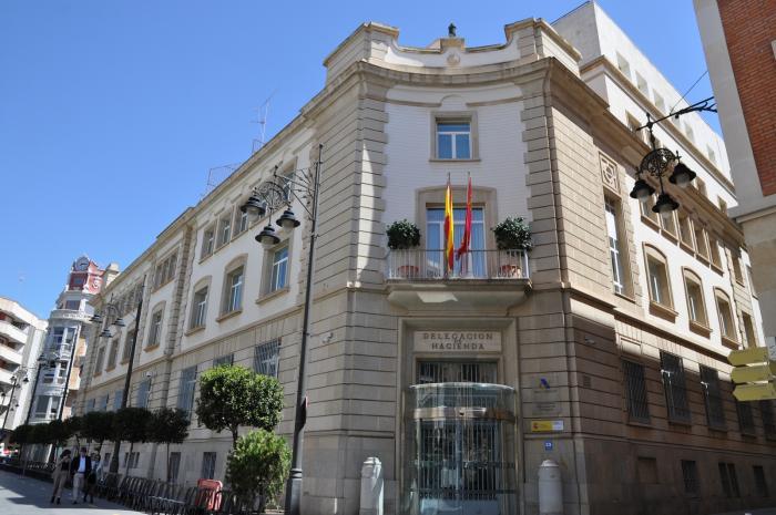 Taxpayer overwhelmed by Spanish Hacienda paperwork with Spain’s flag in the background.