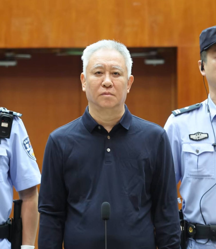 Hui Ka Yan stands between officials at the Shenzhen Intermediate People’s Court during his 2026 sentencing.